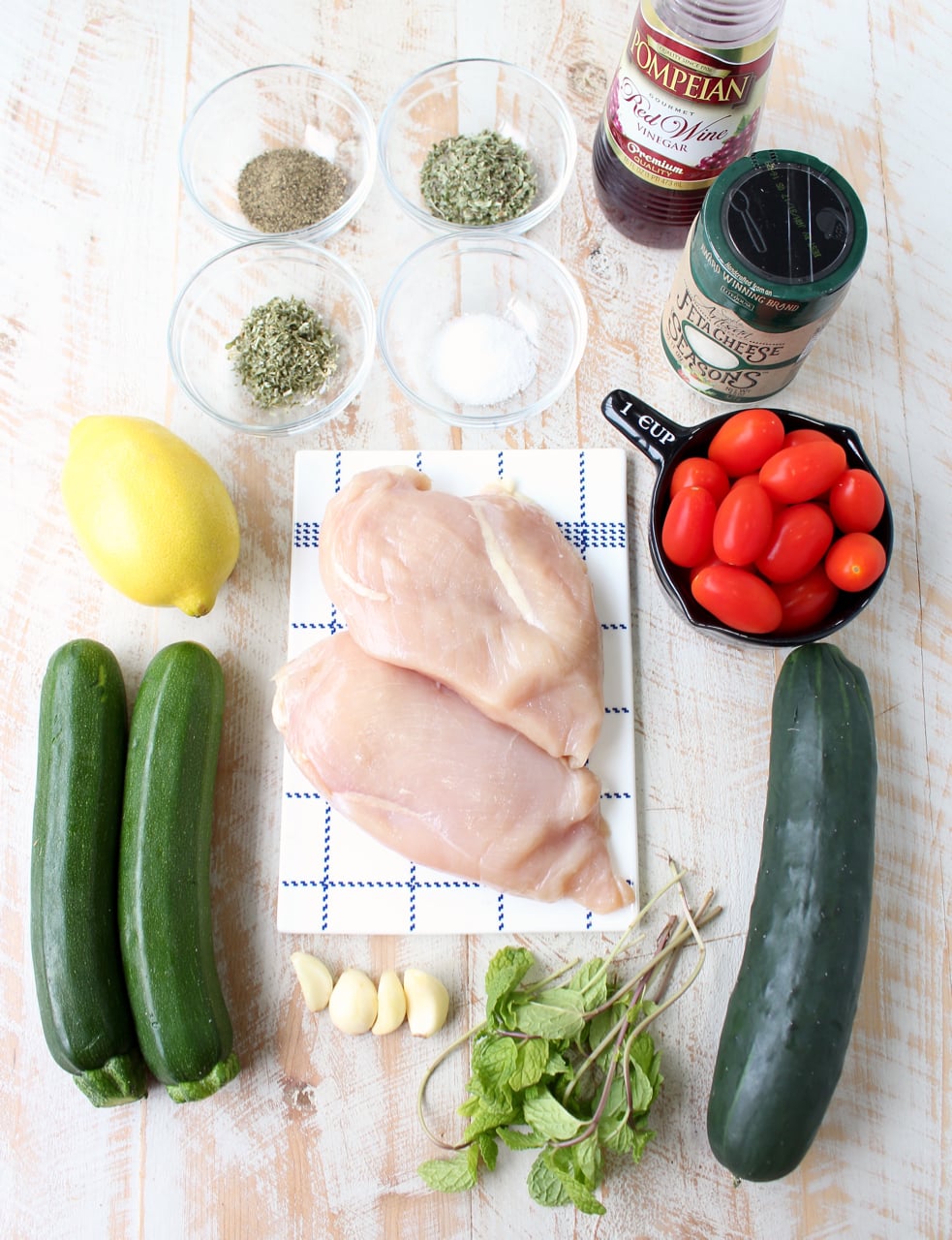 ingredients for Greek chicken zoodle bowls on white wood board