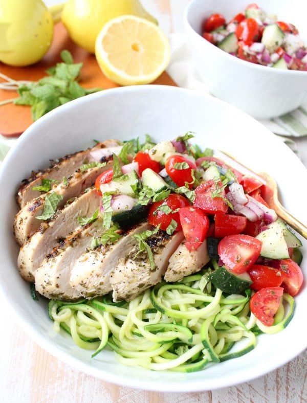 Marinated & grilled Greek Chicken is served on a bowl of zucchini noodles, topped with cucumber tomato salsa for a healthy, gluten free meal made in under 30 minutes!