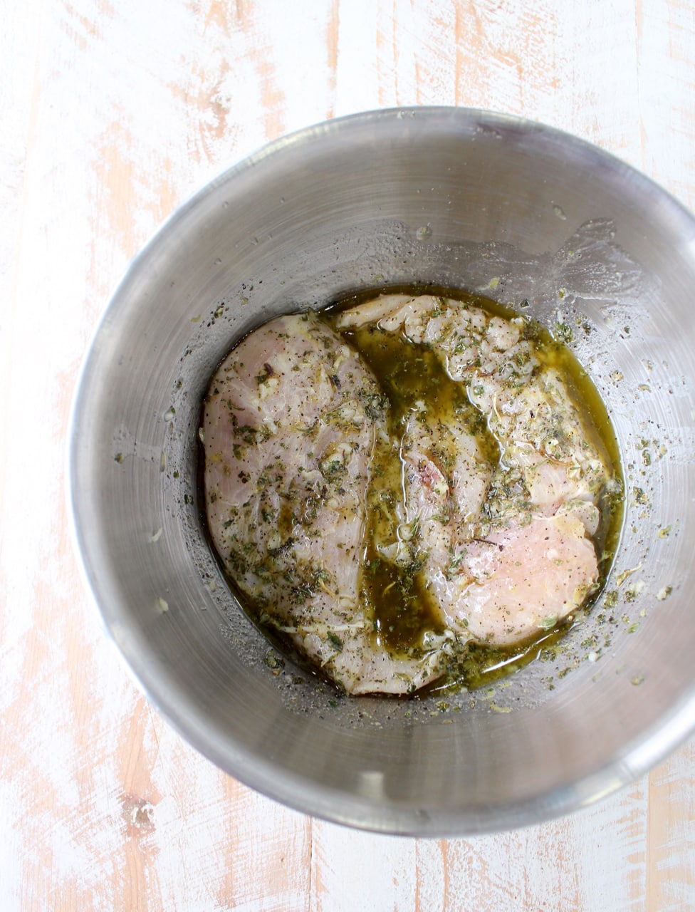 raw chicken in marinade in metal bowl