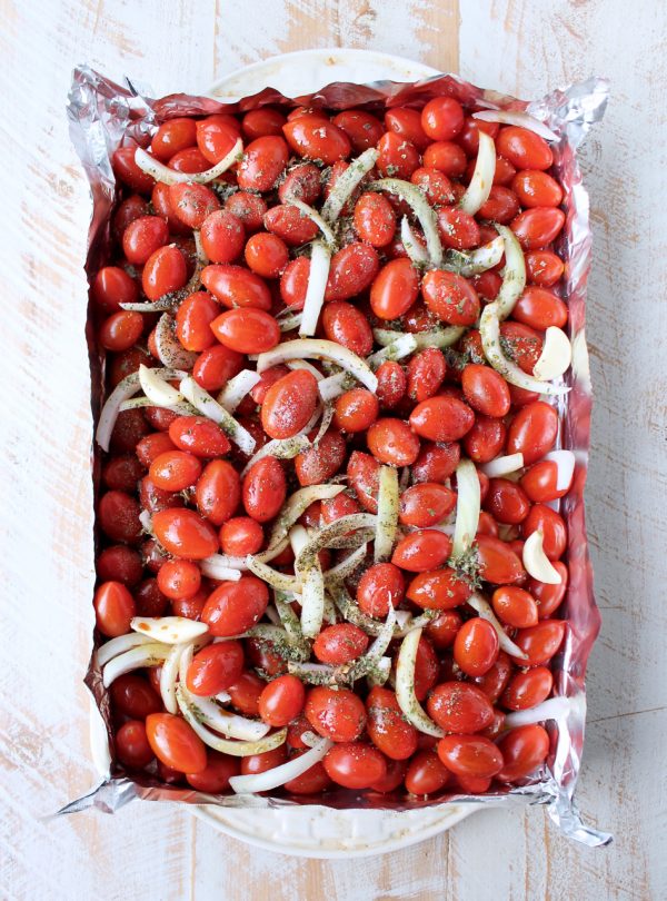 cherry tomatoes and onions with italian seasoning on foil-lined baking sheet