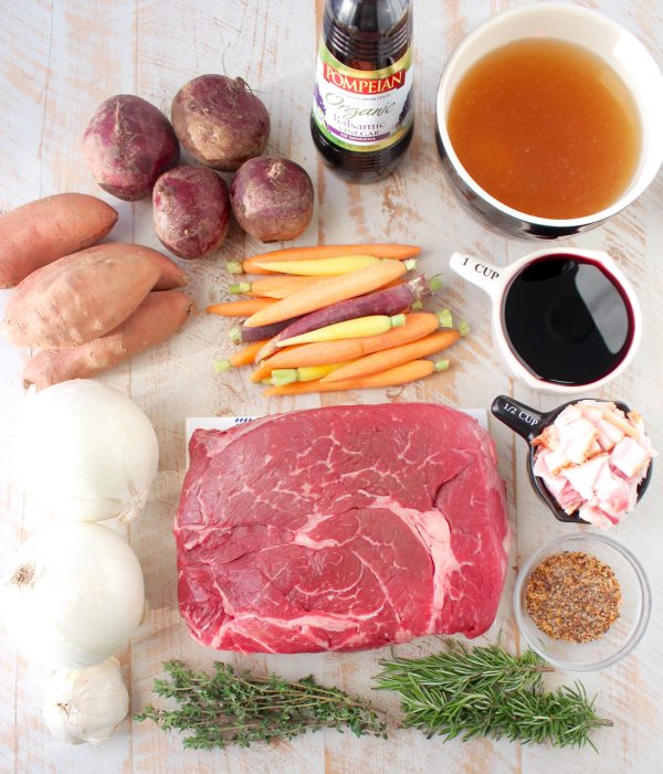 Garlic & herbs are rubbed on a beef chuck, then seared in bacon fat, placed in a crock pot & covered in red wine sauce for a tasty Slow Cooker Pot Roast!