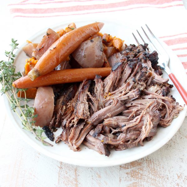Garlic & herbs are rubbed on a beef chuck, then seared in bacon fat, placed in a crock pot & covered in red wine sauce for a tasty Slow Cooker Pot Roast!