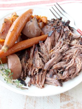 Garlic & herbs are rubbed on a beef chuck, then seared in bacon fat, placed in a crock pot & covered in red wine sauce for a tasty Slow Cooker Pot Roast!