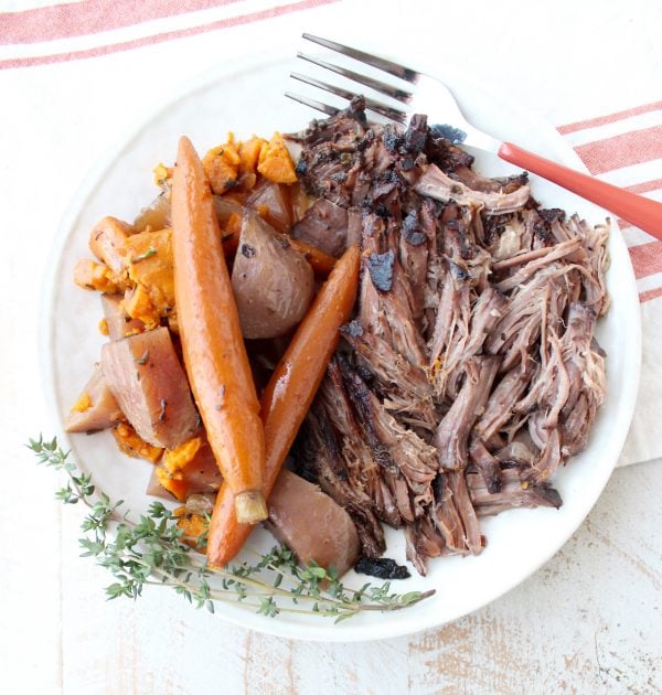 Garlic & herbs are rubbed on a beef chuck, then seared in bacon fat, placed in a crock pot & covered in red wine sauce for a tasty Slow Cooker Pot Roast!