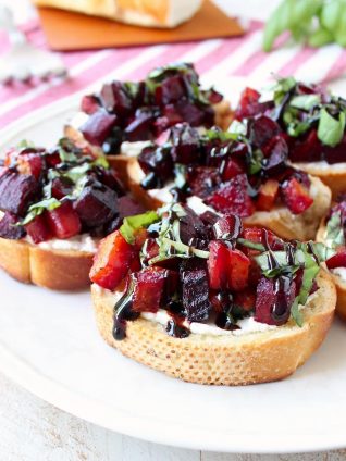 A toasted baguette is topped with goat cheese, balsamic roasted beets, fresh basil & balsamic reduction in this vegetarian Beet Bruschetta recipe that's perfect for Spring!