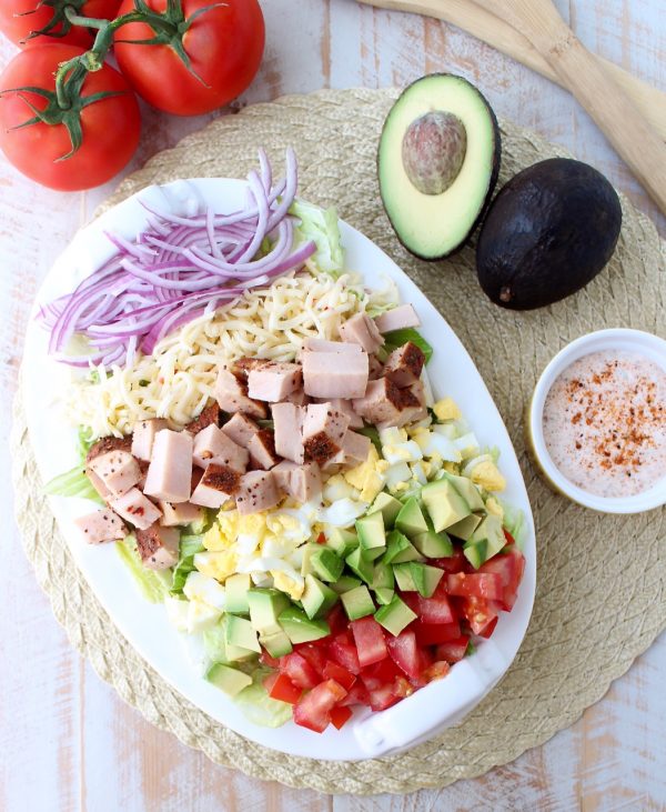 This gluten free Cobb Salad recipe is colorful, flavorful & so easy to make! It's topped with Cajun turkey, avocado, tomatoes & creamy Cajun ranch dressing!