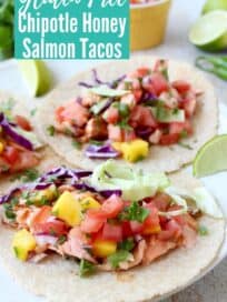 salmon tacos on plate topped with mango salsa