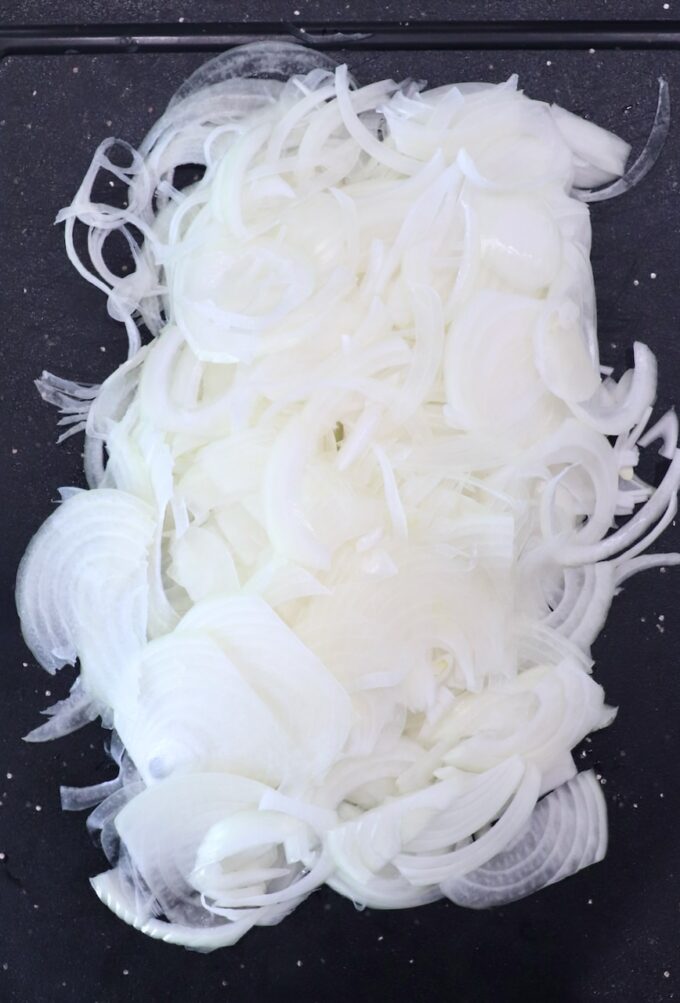 thinly sliced onions on cutting board