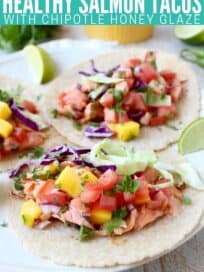 salmon tacos on plate topped with mango salsa