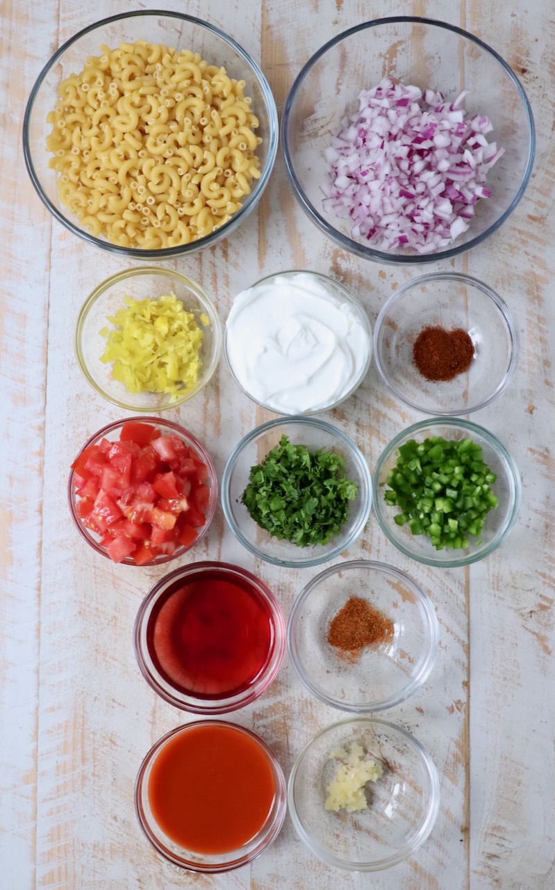 ingredients for spicy macaroni salad on white wood board