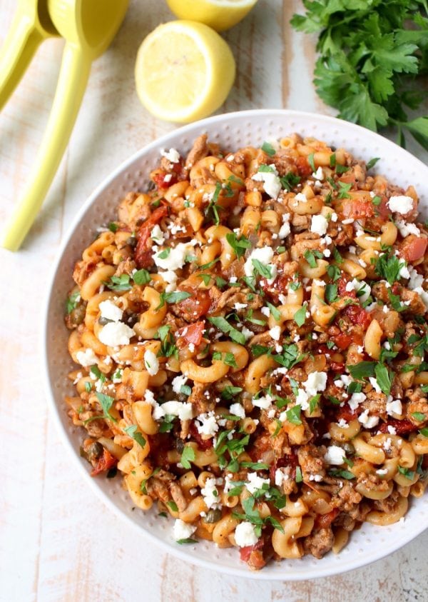 In just one pot and under 45 minutes, make a delicious Greek Pasta recipe filled with sun dried tomatoes, ground turkey, capers and feta cheese!