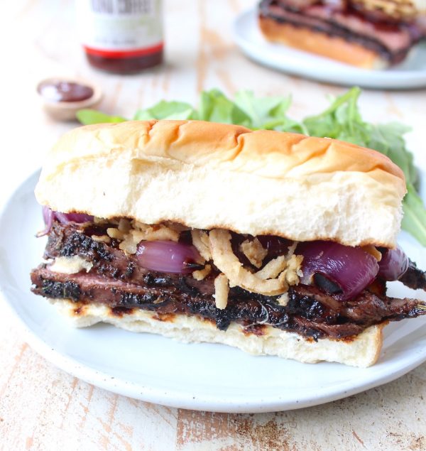 Thin slices of coffee rubbed, grilled steak are piled up with herbed goat cheese, BBQ sauce & grilled onions in this mouth-watering steak sandwich recipe!