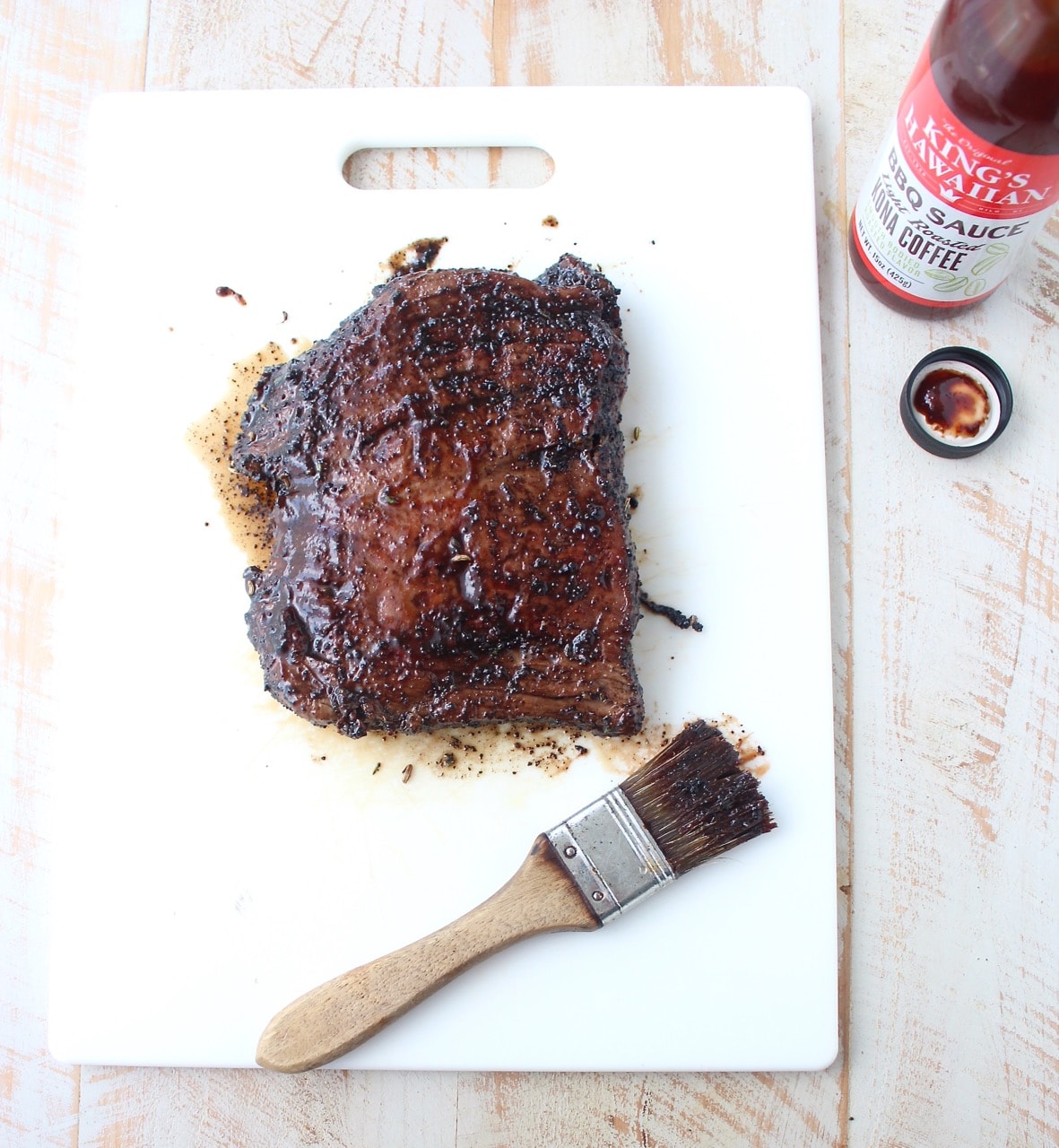 grilled steak covered with bbq sauce on cutting board with pastry brush