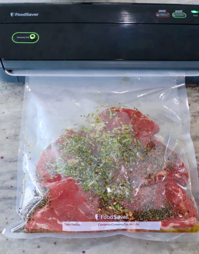 seasoned sirloin steaks in a clear bag in a vacuum sealer