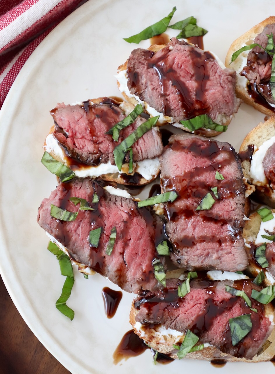 steak crostini topped with balsamic glaze on plate