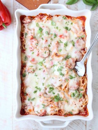 Toss your favorite pizza toppings, like sausage & peppers, with spaghetti & pasta sauce, then top with cheese for an easy pizza baked spaghetti recipe!