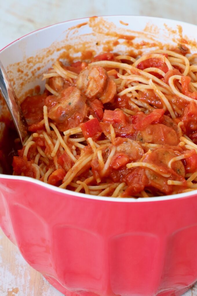 cooked spaghetti tossed with marinara sauce, sausage and peppers in large mixing bowl