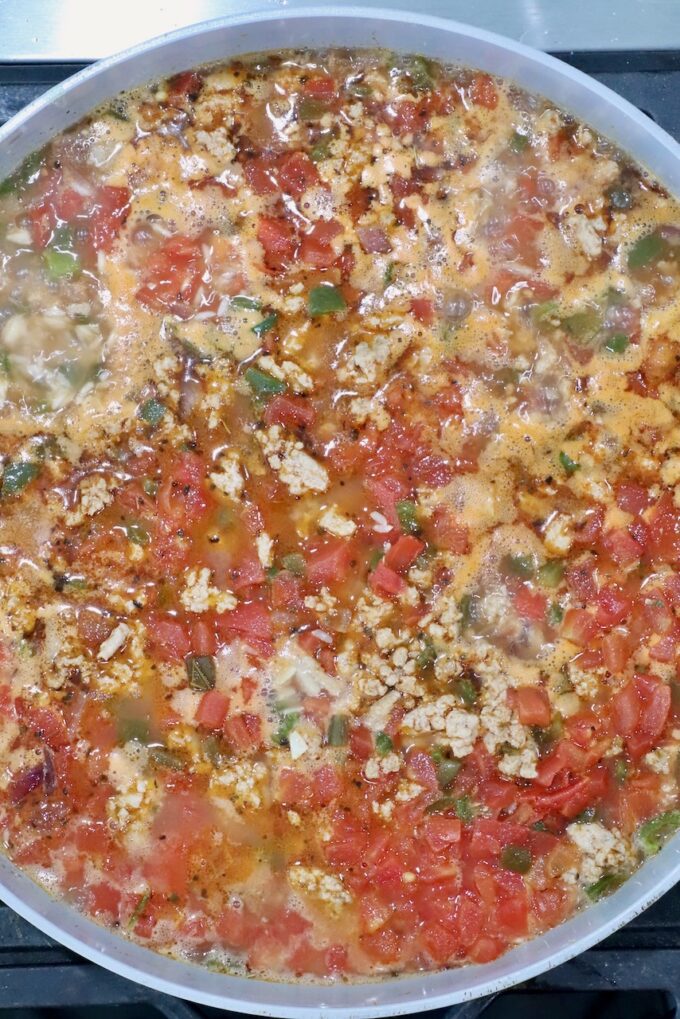 cooked rice, diced tomatoes, and ground turkey in a skillet