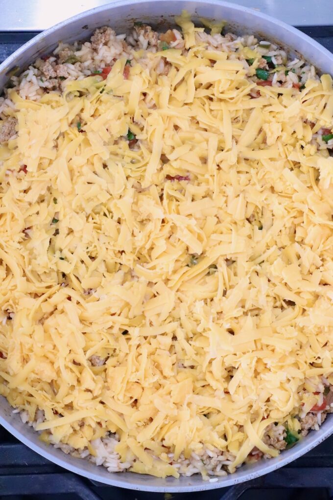 taco rice in a skillet topped with shredded cheddar cheese