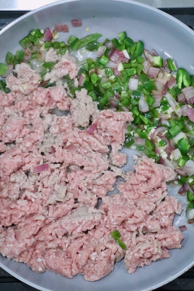 partially cooked ground turkey in a skillet with diced onions and peppers
