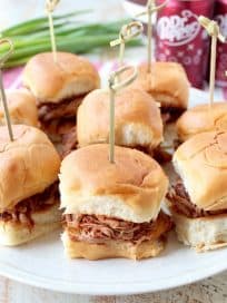 In this tasty slider recipe, pork tenderloin is covered in a delicious spice rub, slow cooked in a Dr Pepper BBQ Sauce, shredded & served on Hawaiian rolls.