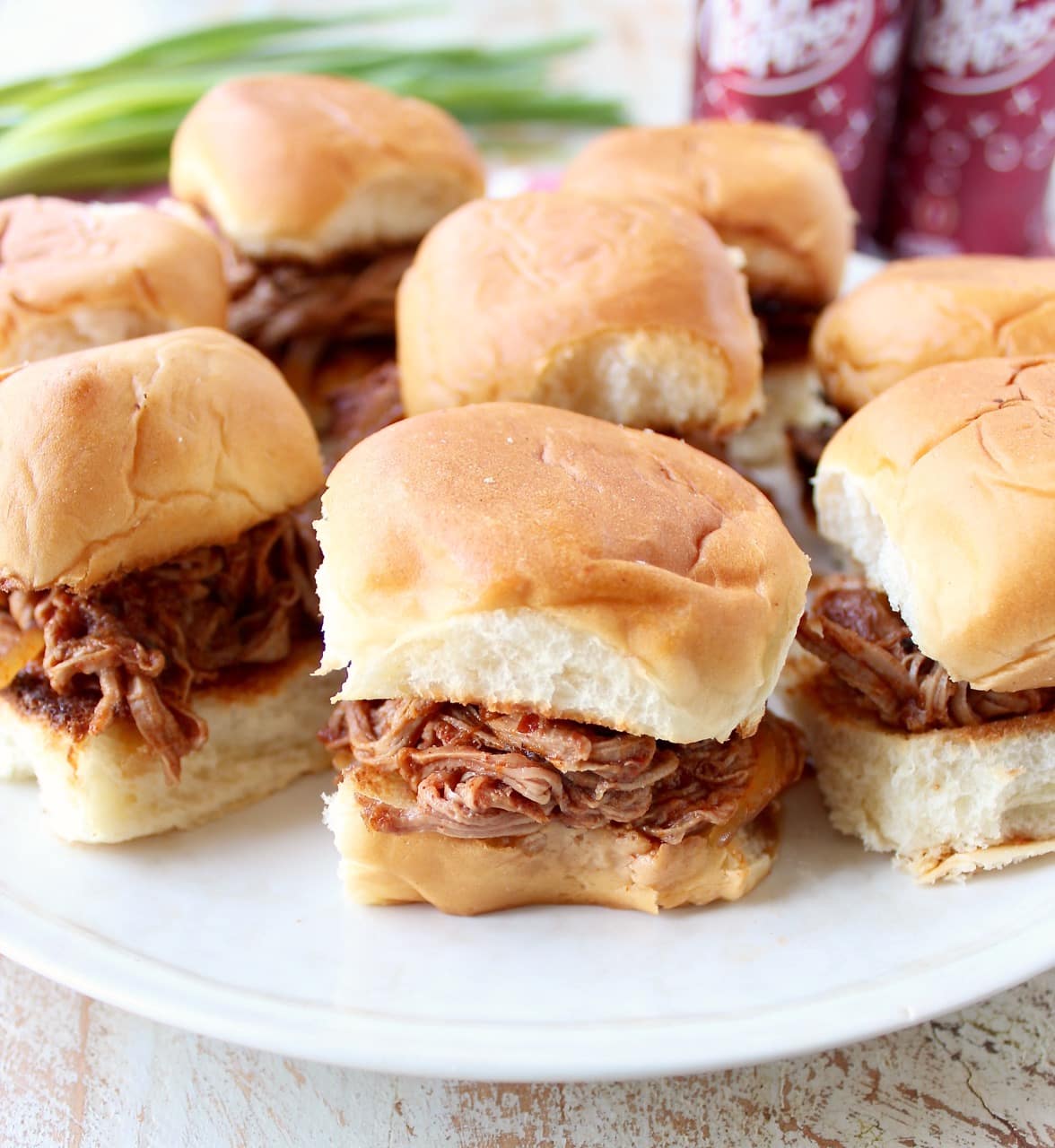 Hawaiian rolls filled with shredded dr pepper pork on a white plate.