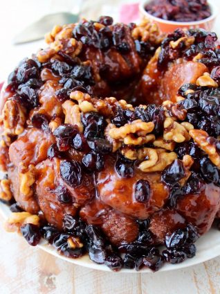 Maple syrup, dried cranberries and walnuts top this decadent monkey bread recipe that's perfect for fall brunches and holiday breakfasts!