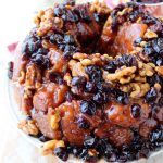 Maple syrup, dried cranberries and walnuts top this decadent monkey bread recipe that's perfect for fall brunches and holiday breakfasts!
