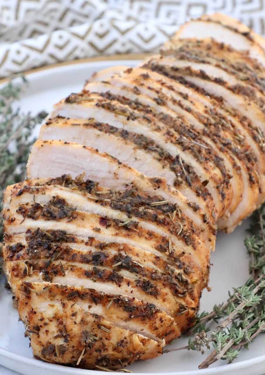 sliced turkey breast on a plate with fresh thyme