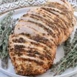 sliced turkey breast on a plate with fresh thyme