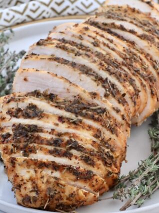 sliced turkey breast on a plate with fresh thyme