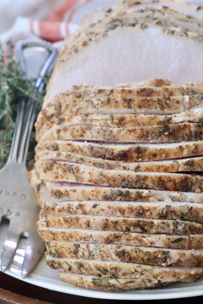 sliced turkey breast on a plate with a large serving fork