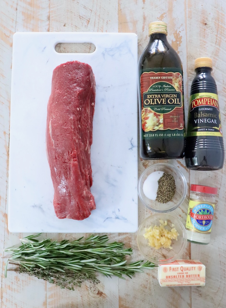 ingredients for herb crusted beef tenderloin on a white wood board