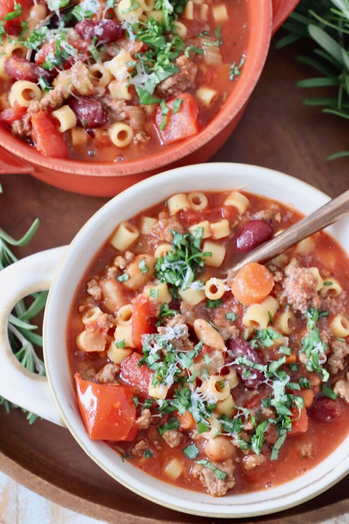 overhead image of pasta fagioli soup in bowls with copper spoon