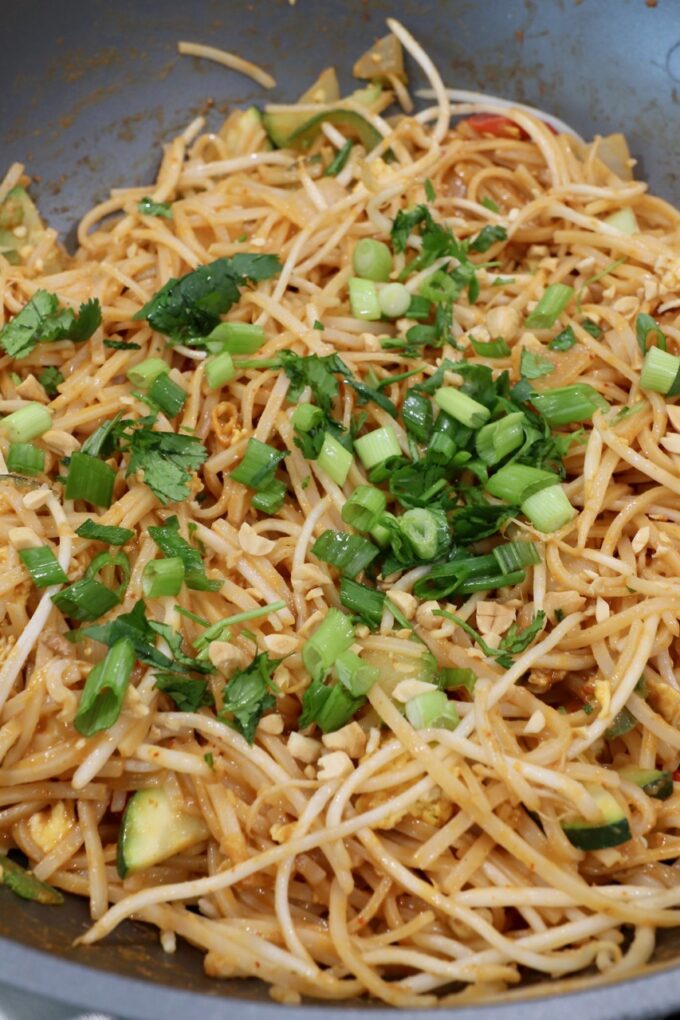 prepared Pad Thai in wok topped with diced green onions and cilantro