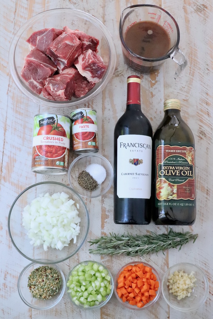 ingredients for beef ragu on a white wood board