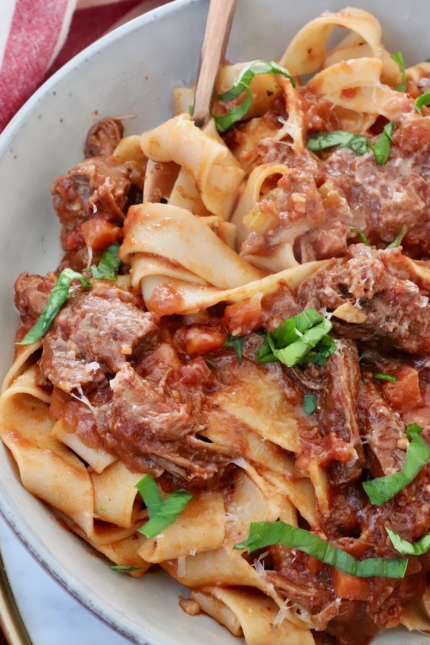 pasta and beef ragu sauce in a bowl with a fork