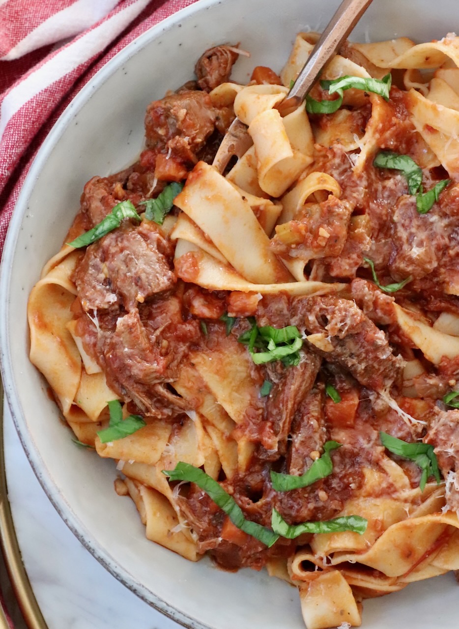 beef ragu sauce tossed with pasta in a bowl with a fork