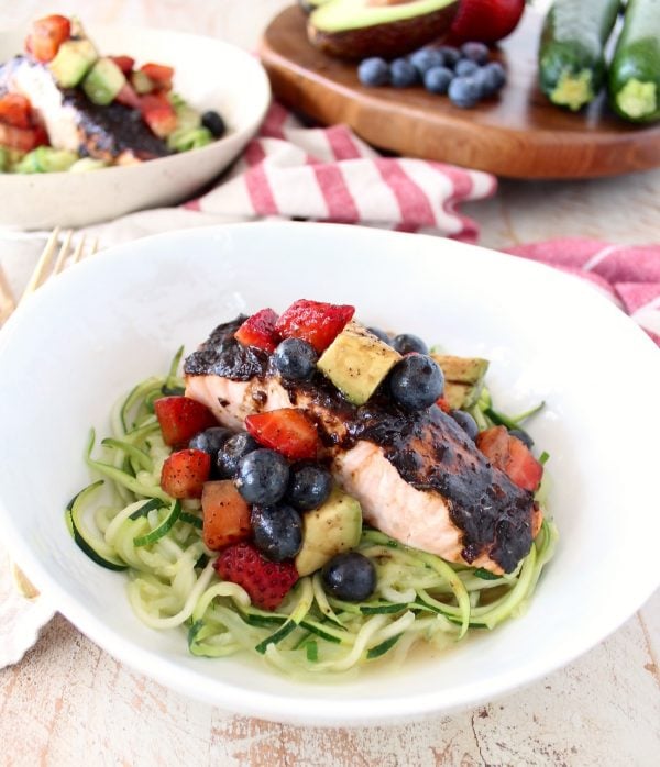 Roasted balsamic salmon is served over zucchini noodles topped with a berry avocado salsa for a flavorful meal that's easy to make, gluten free, dairy free and Whole 30 approved!