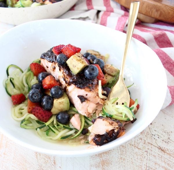 Roasted balsamic salmon is served over zucchini noodles topped with a berry avocado salsa for a flavorful meal that's easy to make, gluten free, dairy free and Whole 30 approved!