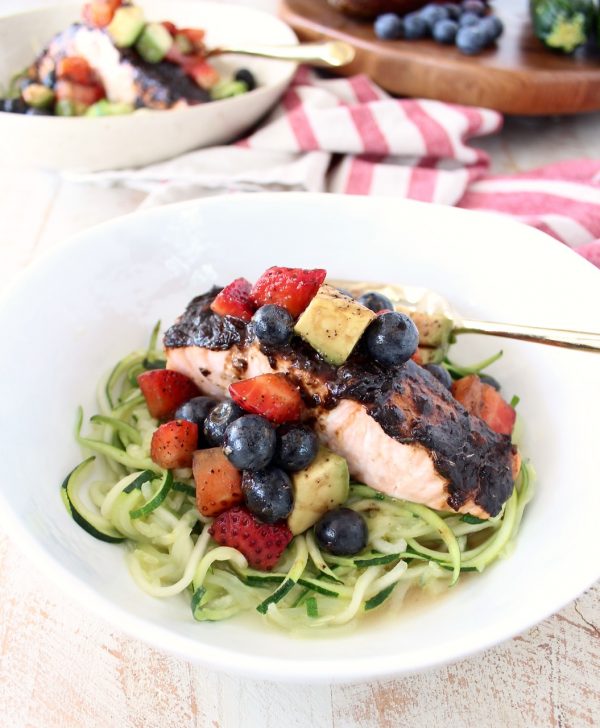 Roasted balsamic salmon is served over zucchini noodles topped with a berry avocado salsa for a flavorful meal that's easy to make, gluten free, dairy free and Whole 30 approved!