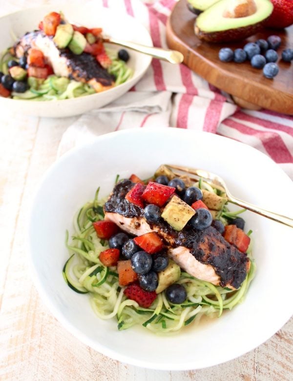 Roasted balsamic salmon is served over zucchini noodles topped with a berry avocado salsa for a flavorful meal that's easy to make, gluten free, dairy free and Whole 30 approved!