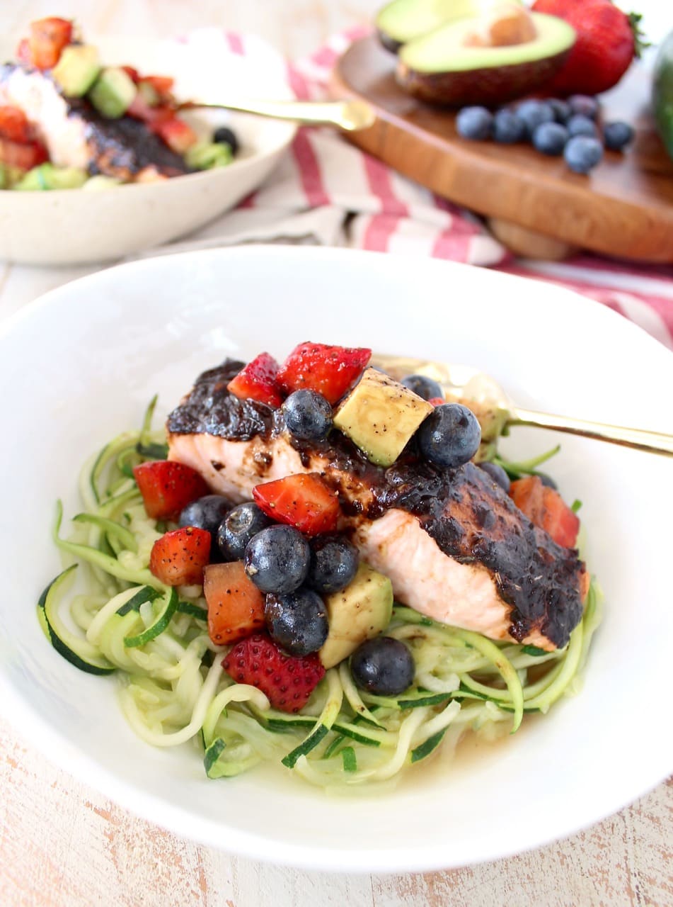 Roasted balsamic salmon is served over zucchini noodles topped with a berry avocado salsa for a flavorful meal that's easy to make, gluten free, dairy free and Whole 30 approved!