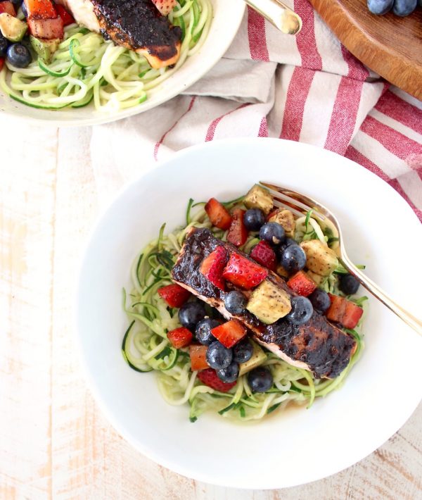 Roasted balsamic salmon is served over zucchini noodles topped with a berry avocado salsa for a flavorful meal that's easy to make, gluten free, dairy free and Whole 30 approved!