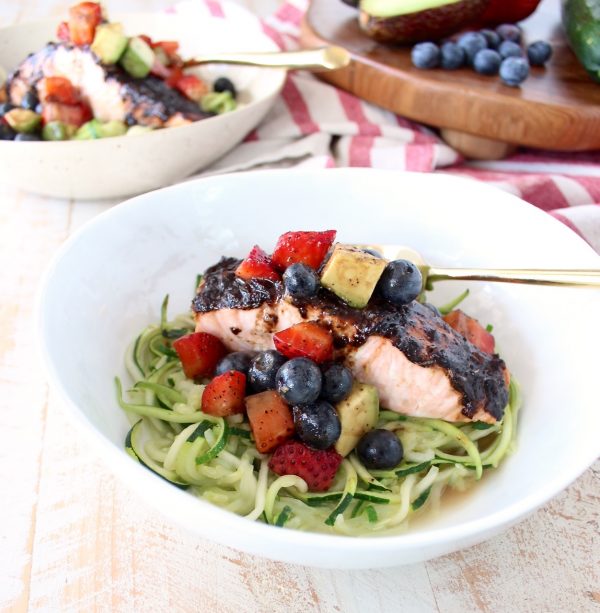 Roasted balsamic salmon is served over zucchini noodles topped with a berry avocado salsa for a flavorful meal that's easy to make, gluten free, dairy free and Whole 30 approved!