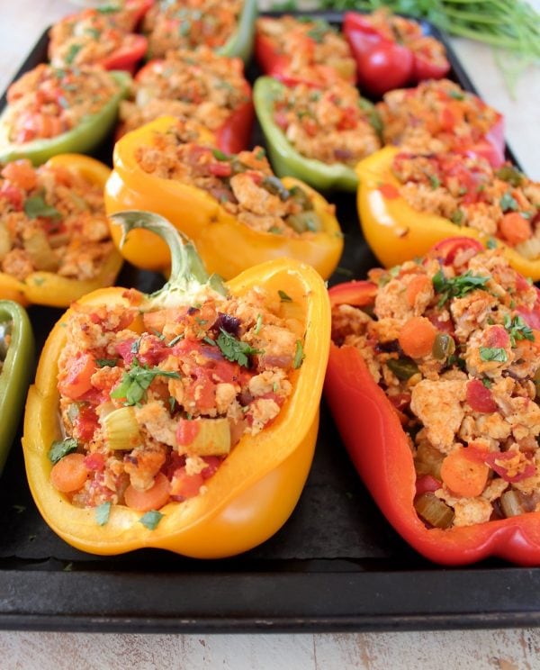Cooked ground chicken, carrots and celery stuffed in bell pepper halves on baking sheet
