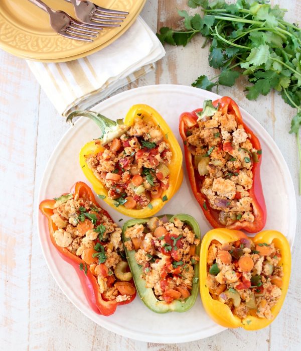 Overhead shot of buffalo chicken stuffed peppers on white plate with cilantro on the side