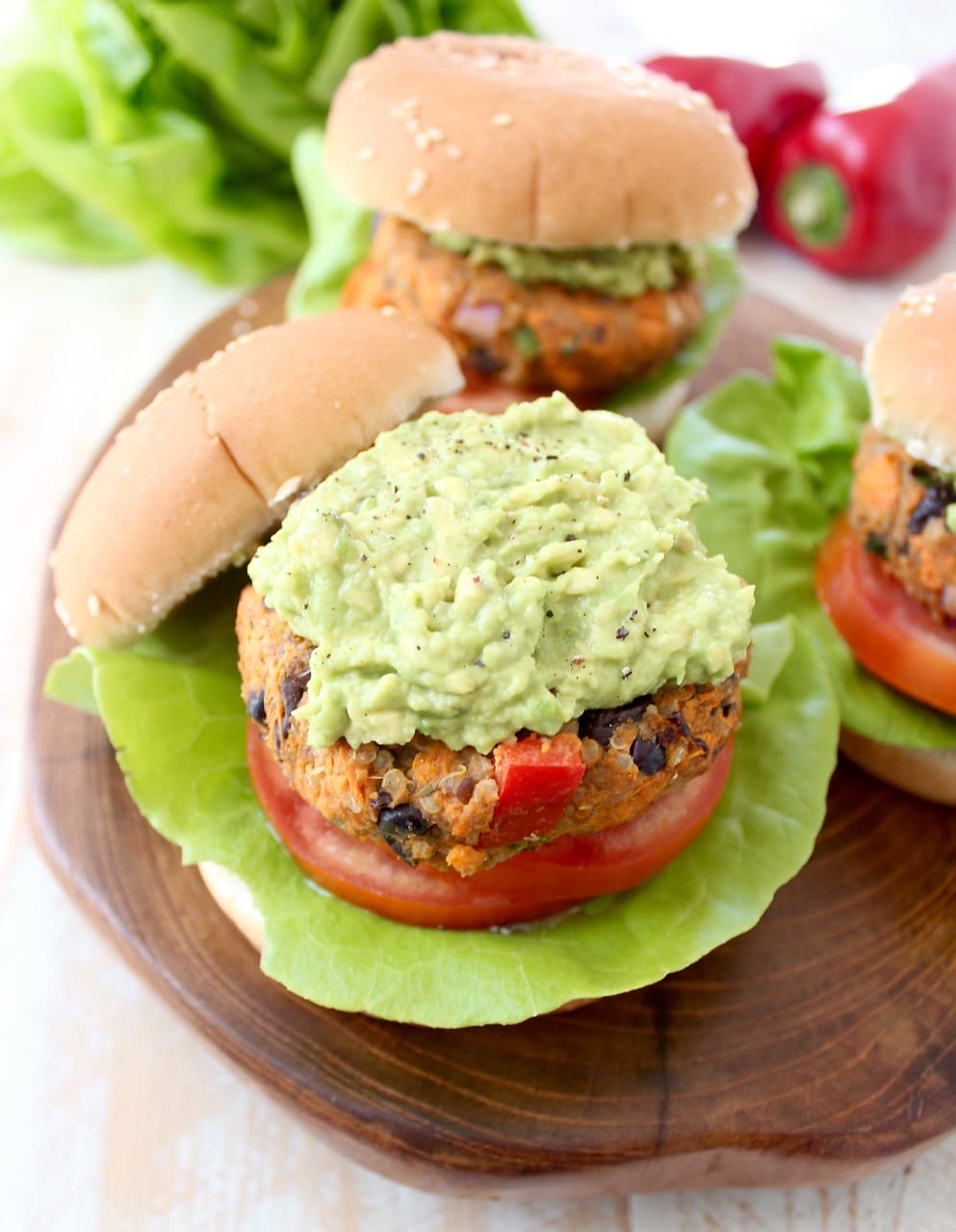 Veggie Burgers topped with mashed Avocado on a wood board