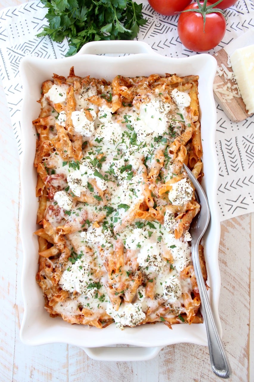 baked pasta with cheese in white casserole dish with large serving fork