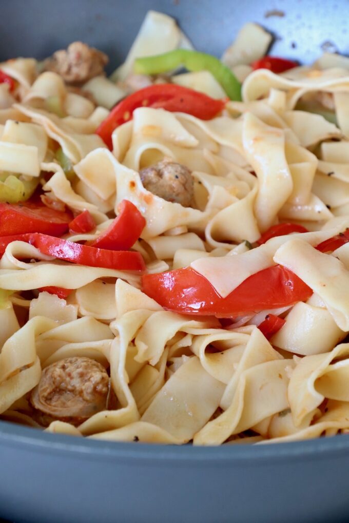 sliced bell peppers tossed with cooked noodles in large pan